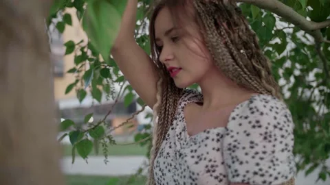 A cute girl with dreadlocks poses by a tree with leaves Stock Footage 154628901
