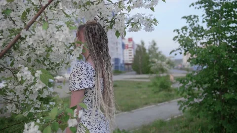 A cute girl with dreadlocks poses by a tree with leaves Stock Footage 154637811