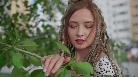 A cute girl with dreadlocks poses by a tree with leaves Stock Footage 154714800