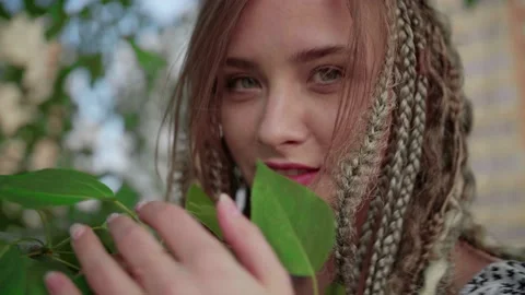 A cute girl with dreadlocks poses by a tree with leaves Video stock 154715369