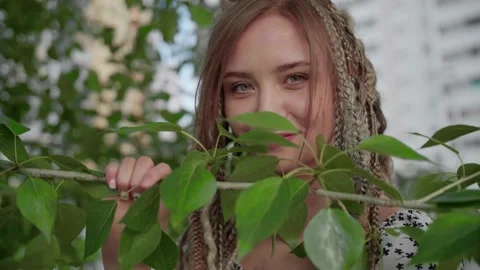 A cute girl with dreadlocks poses by a tree with leaves Stock Footage 154722968