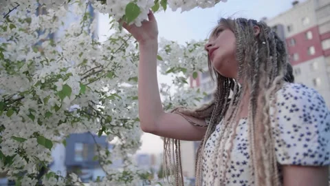 A cute girl with dreadlocks poses by a tree with leaves Stock Footage 154723973