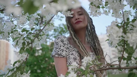A cute girl with dreadlocks poses by a tree with leaves Stock Footage 154724063