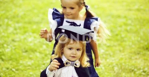 Cute girl dressing small boy in graduation hat and robe Stock Photos