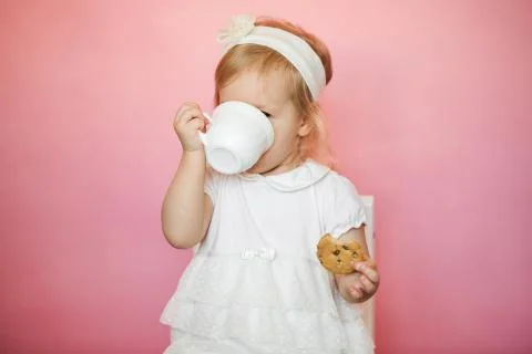 Cute girl has breakfast, eats cookies and drinks kefir from a cup Stock Photos