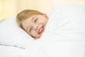 The cute girl lay on the bed with white linens Photo