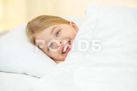 The cute girl lay on the bed with white linens Stock Photos