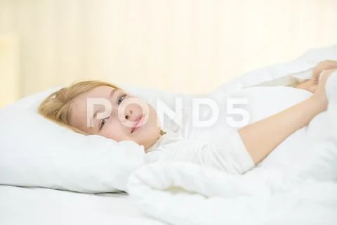 The cute girl lay on the bed with white linens Stock Photos