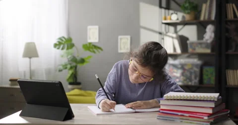 Cute girl learning online using study app on digital tablet, watching Stock Footage 271670520