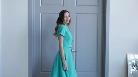 Cute girl model posing on grey door background smiling in grey dress.Slow motion Stock Footage 107829818