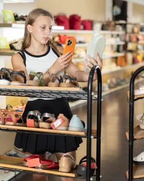 Cute girl scans QR code on the label of new sneakers in shoe store Foto stock