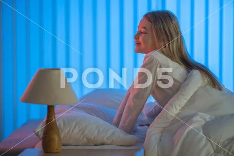 The cute girl sitting on the bed. Evening night time Stock Photos