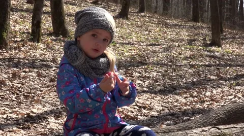 Cute Girl Sitting on Old Pine Tree in Early Spring Forest and Playing. 4K UltraH Stock Footage 49269953