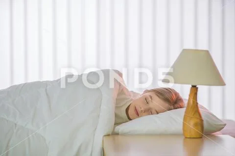 The cute girl sleeping on the bed with white linens Stock Photos