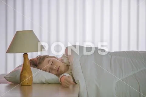 The cute girl sleeping on the bed with white linens Stock Photos