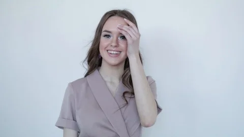 Cute girl smiling model posing in a gray dress on a gray background .Slow motion Stock Footage 107826942