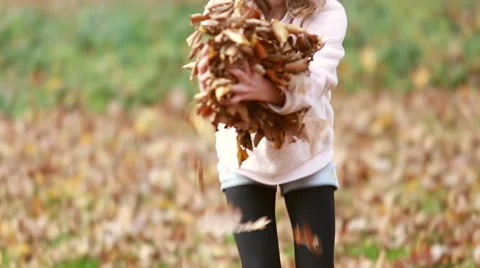 Cute girl throwing leaves in park Stock Footage 59554399