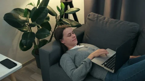 Cute girl using laptop notebook lying on sofa under night lamp at home Stock-Footage 202122282