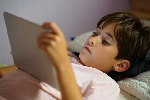 Cute girl using a tablet computer in her bedroom Stock Photos