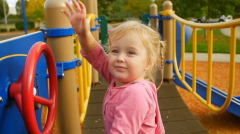 Cute girl waves at camera while turning a large wheel Stock Footage 58637606