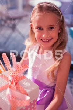 Cute girl wearing new dress and holding her birthday present Stock Photos
