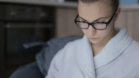 Cute girl working on a laptop while at home in a bathrobe sitting in the chair Stock Footage 71222090