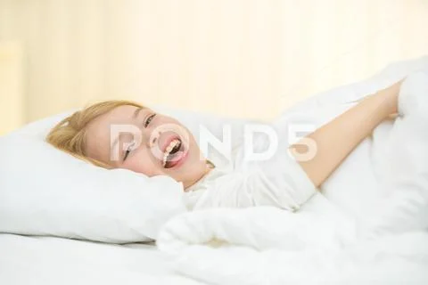 The cute girl yawn and lay on the bed Stock Photos