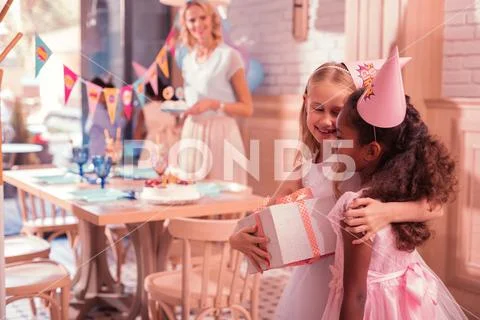 Cute girls hugging and smiling while being at the birthday party Stock Photos