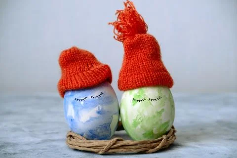 Cute green and blue easter in orange knitted hats Stock Photos