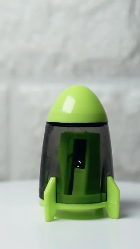 Cute green rocket-shaped pencil sharpener spinning on a white surface, show.. Stock Footage 297160283