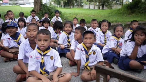Cute group of Thai students in boy scout uniform sits together in the park Stock Footage 157059732