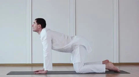 Cute Guy Doing Yoga. He Sits in a White Suit. Marjari Asana Stock-Footage 59730209