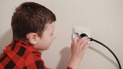 Cute guy in red black plaid shirt rubs hands, pulls electric plug out of socket Stock Footage 125051368