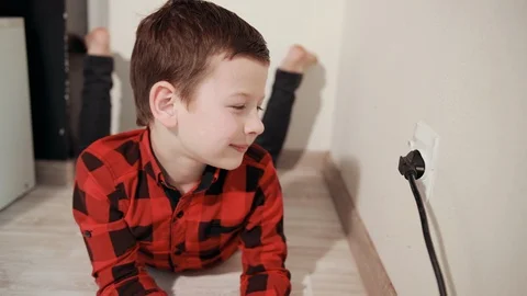 Cute guy in red black plaid shirt rubs hands, pulls electric plug out of socket Stock Footage 125131334