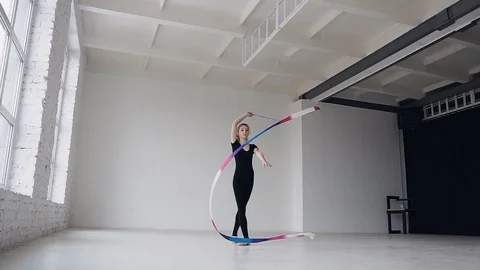 Cute gymnastics in black body performs the gymnastics exercise with a colored Video stock 88555517