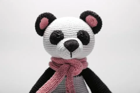 Cute handmade toy. knitted little animal. panda with a scarf on the neck. on Photos