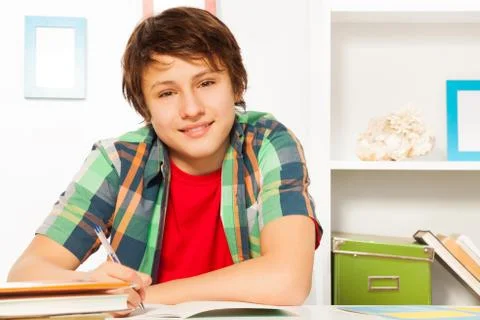 Cute handsome boy write in textbook and smile Stock Photos