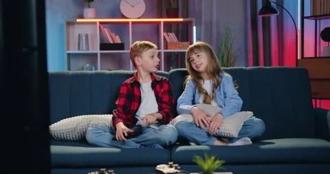 Cute happy smiling 10-aged brother and sister sitting in front of TV in living Stock Footage 158099245