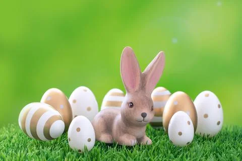 Cute hare surrounded by Easter eggs in a grassy meadow. Stock Photos