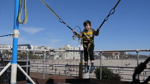 CUTE HISPANIC BOY BUNGEE SUMERSAULTS AT AMUSEMENT PARK. Stock Footage 63319772