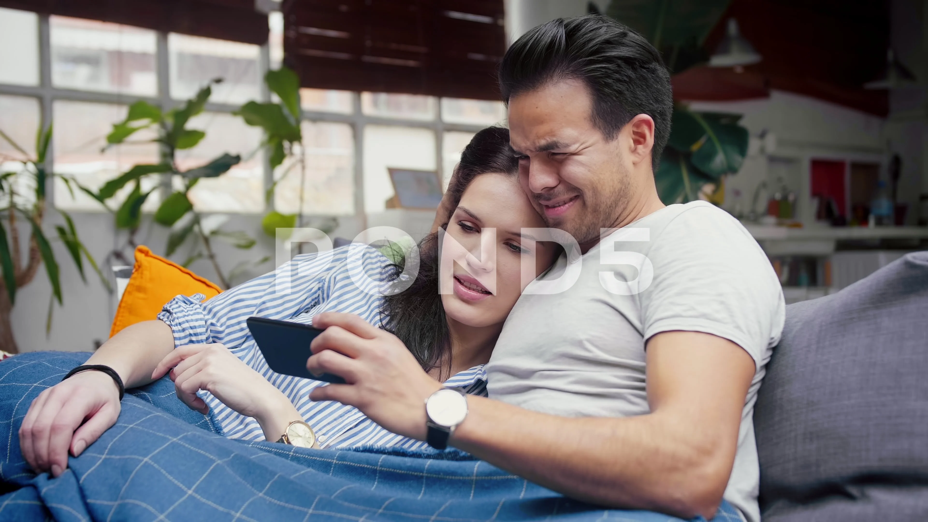 Cute Hispanic couple chilling in cosy living room, watching video in YouTube