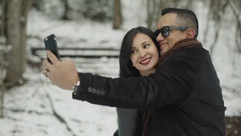 Cute hispanic latin couple doing selfie in the snow park Stock Footage 88066392