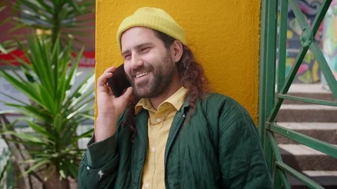 Cute Hispanic man talking on telephone with friends standing near yellow wall Stock Footage 108428190