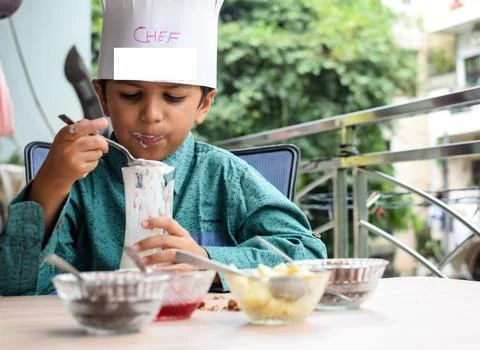 Cute Indian chef boy preparing sundae dish as a part of non fire cooking wh.. Foto stock