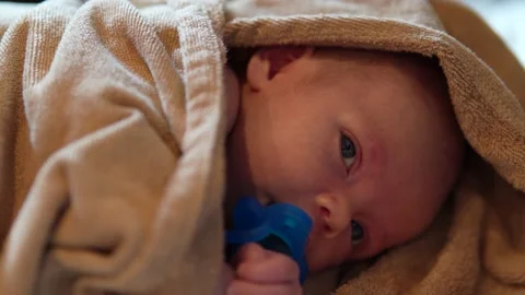 Cute infant with a pacifier, wrapped in a towel after bath Stock-Footage 157836364