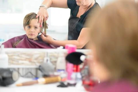 Cute innocent boy looking in the mirror at barbershop Stock Photos