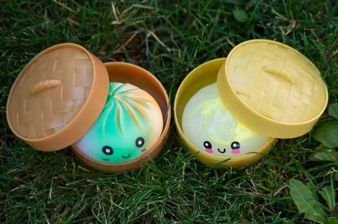 Cute kawaii dumpling squishies inside open steamer baskets on grass Stock Photos