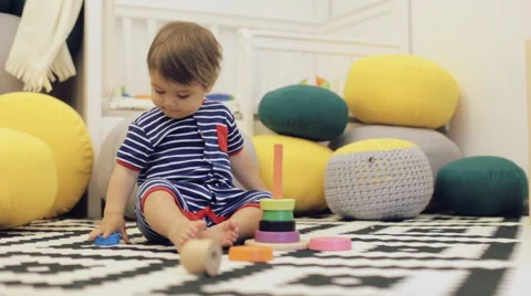 Cute kid in blue bodysuit playing colorful tower at floor Stock Footage 64522435