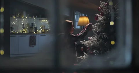 Cute kid boy decorating Christmas tree with balls, view from window, snow Stock Footage 293739967