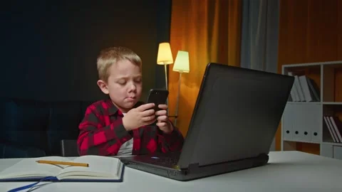 Cute kid boy holding smart phone enjoying using mobile apps, playing games at Stock Footage 169865835
